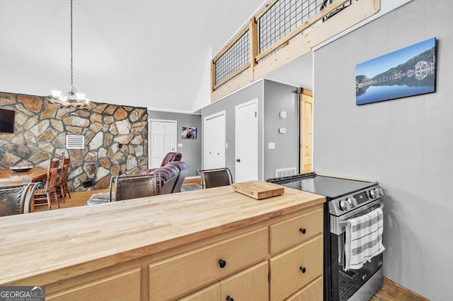 kitchen with pendant lighting, butcher block countertops, an inviting chandelier, high vaulted ceiling, and stainless steel range with electric cooktop