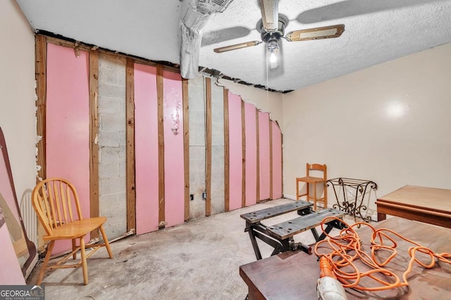 miscellaneous room with ceiling fan, concrete flooring, and a textured ceiling