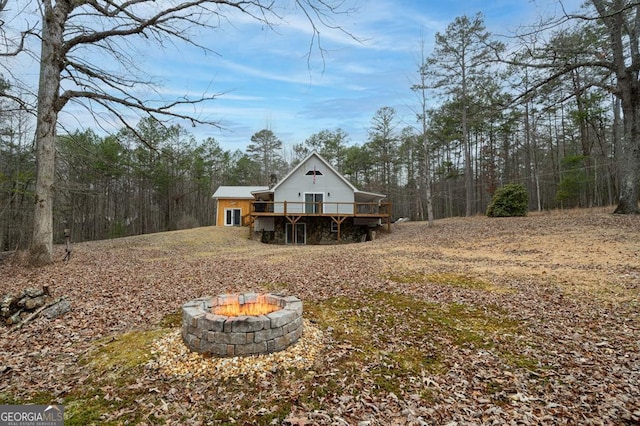 rear view of property with a wooden deck and a fire pit