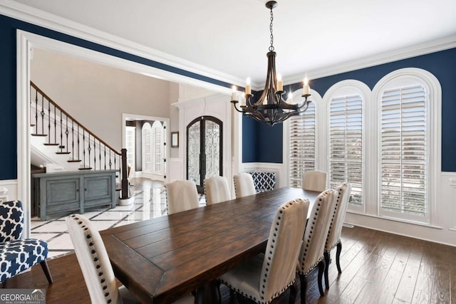 dining room with wood-type flooring, ornamental molding, a chandelier, and french doors