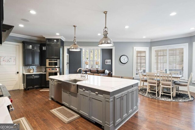 16143 Belford Dr, Alpharetta, GA 30004 - kitchen featuring a sink, appliances with stainless steel finishes, a center island with sink, dark wood-style floors, and hanging light fixtures