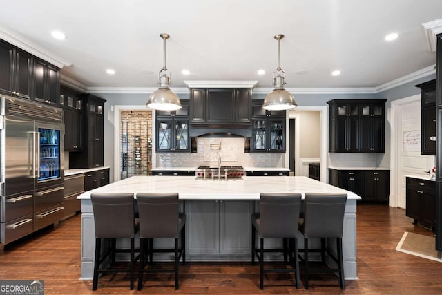 kitchen with stainless steel built in refrigerator, a large island, a breakfast bar area, and decorative light fixtures