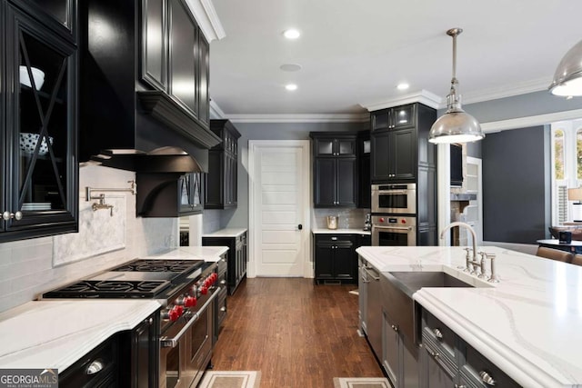 kitchen featuring appliances with stainless steel finishes, dark hardwood / wood-style floors, light stone counters, ornamental molding, and decorative light fixtures