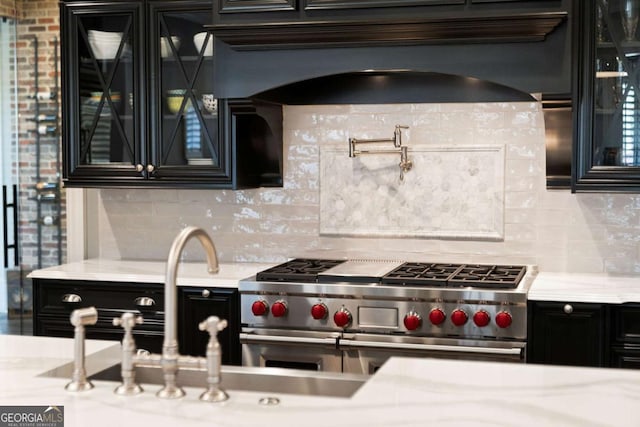 kitchen with range with two ovens, light stone countertops, custom range hood, and backsplash