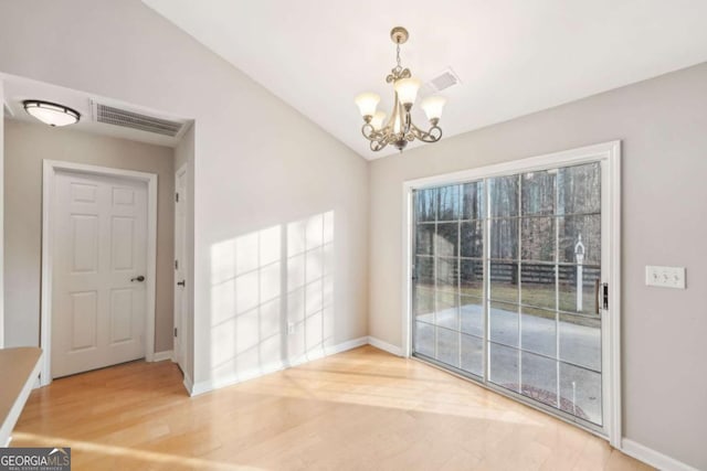 unfurnished dining area featuring hardwood / wood-style flooring, vaulted ceiling, and an inviting chandelier