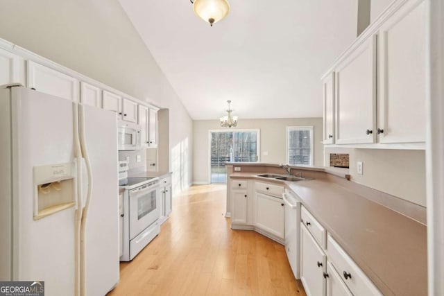 kitchen featuring sink, vaulted ceiling, kitchen peninsula, white appliances, and white cabinets