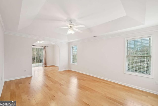 unfurnished room featuring a raised ceiling, crown molding, ceiling fan, and light hardwood / wood-style flooring