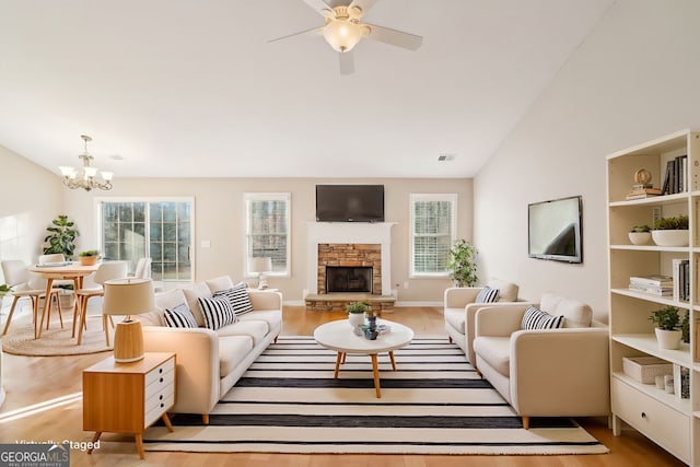 living room with lofted ceiling, a healthy amount of sunlight, a fireplace, and light hardwood / wood-style floors