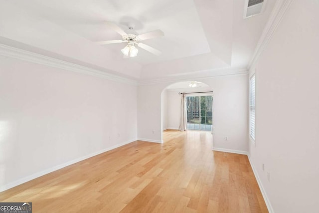 unfurnished room featuring crown molding, light hardwood / wood-style flooring, a raised ceiling, and ceiling fan