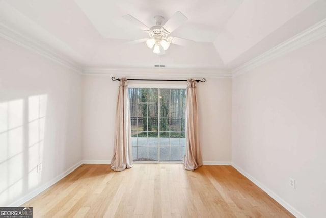 spare room featuring ceiling fan, ornamental molding, a raised ceiling, and light hardwood / wood-style flooring