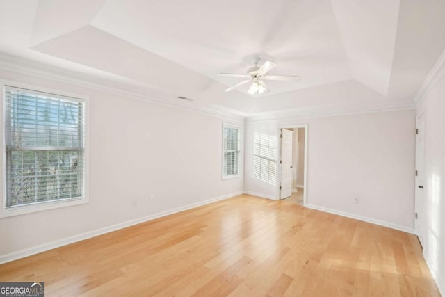 unfurnished room with crown molding, a tray ceiling, ceiling fan, and light wood-type flooring