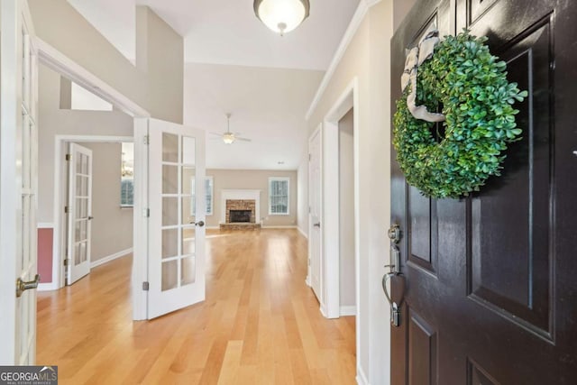 foyer featuring ceiling fan, a fireplace, french doors, and wood-type flooring