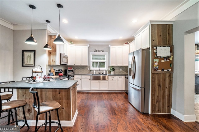 kitchen with sink, white cabinetry, hanging light fixtures, appliances with stainless steel finishes, and a kitchen breakfast bar