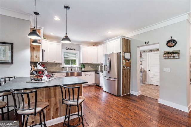 kitchen featuring decorative light fixtures, white cabinetry, sink, kitchen peninsula, and stainless steel appliances