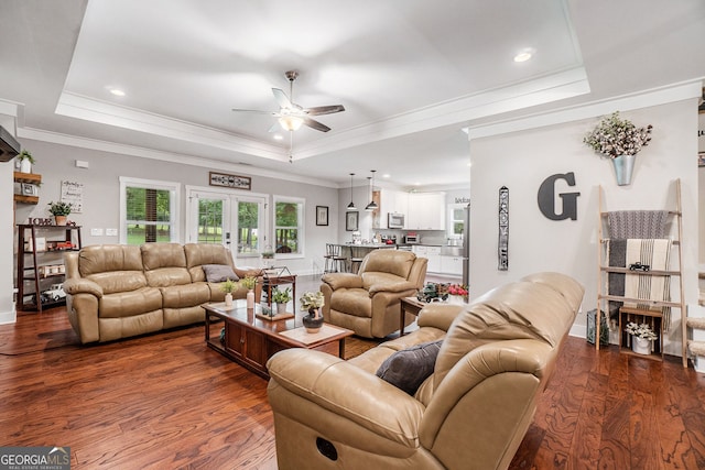 living room featuring hardwood / wood-style flooring, ornamental molding, a raised ceiling, and french doors