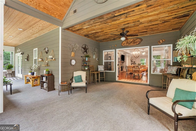 living area with vaulted ceiling, ceiling fan with notable chandelier, wood walls, carpet, and wooden ceiling