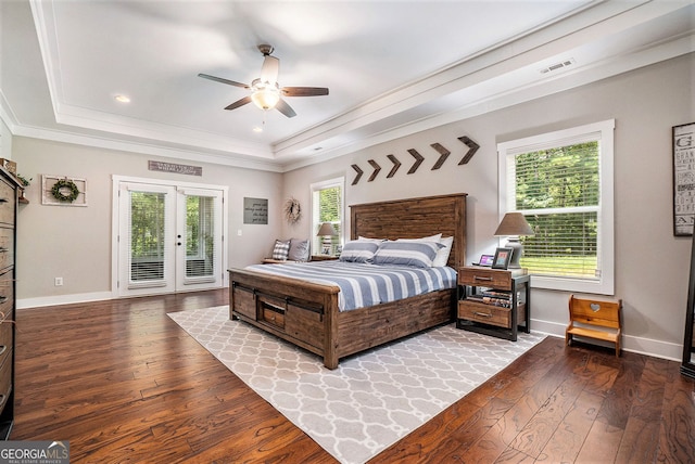 bedroom featuring wood-type flooring, access to outside, a tray ceiling, crown molding, and french doors