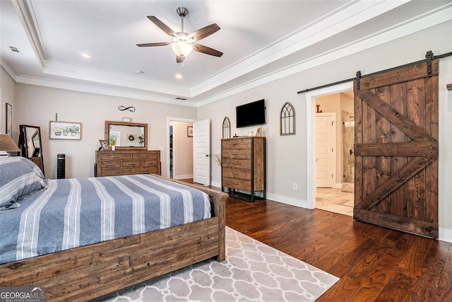 bedroom with a raised ceiling, ornamental molding, a barn door, and dark wood-type flooring