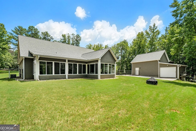 rear view of property featuring a garage, a sunroom, a fire pit, and a lawn