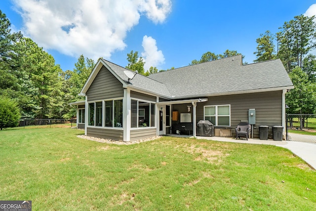 back of property with a sunroom, a yard, and a patio area