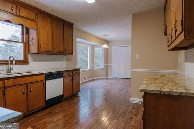 kitchen featuring dark wood-type flooring, sink, hanging light fixtures, dishwasher, and backsplash