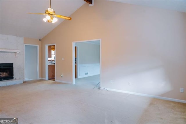 unfurnished living room featuring a tiled fireplace, high vaulted ceiling, light colored carpet, and ceiling fan