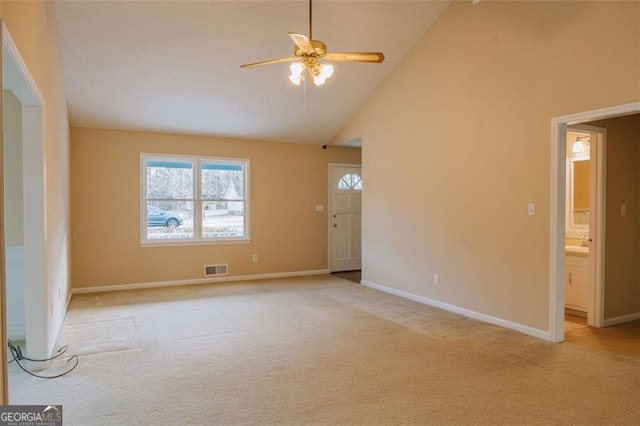 carpeted empty room with ceiling fan and high vaulted ceiling