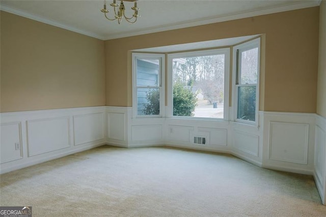 carpeted empty room with crown molding and an inviting chandelier