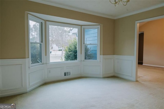 carpeted spare room with ornamental molding and a chandelier