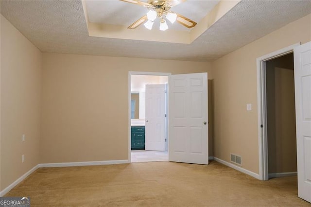 carpeted spare room featuring ceiling fan, a raised ceiling, and a textured ceiling