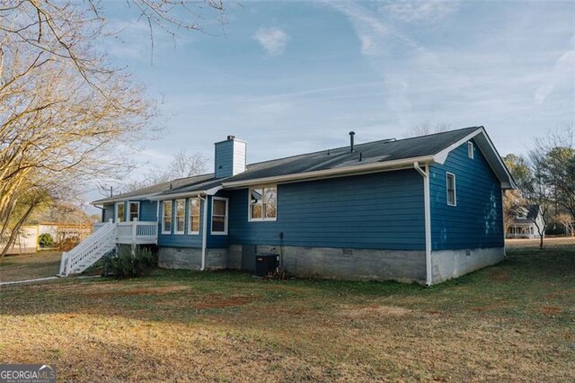 view of front of home with cooling unit and a front lawn