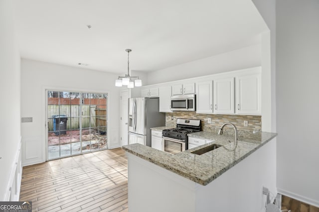 kitchen with pendant lighting, white cabinetry, sink, kitchen peninsula, and stainless steel appliances