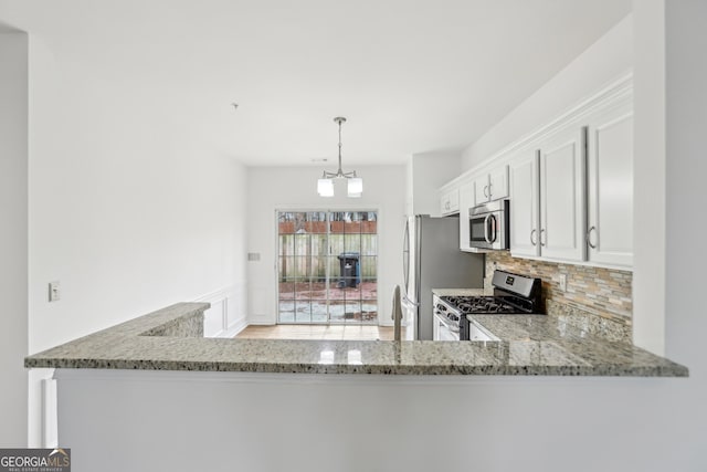 kitchen featuring decorative light fixtures, white cabinetry, decorative backsplash, stainless steel appliances, and light stone countertops