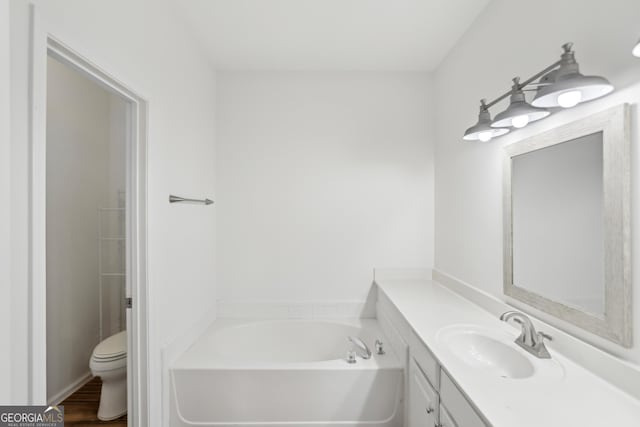 bathroom with hardwood / wood-style flooring, vanity, toilet, and a bathtub