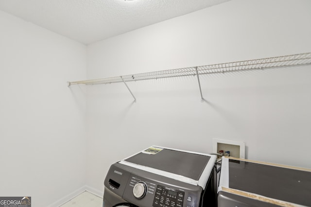 clothes washing area featuring washer / dryer and a textured ceiling