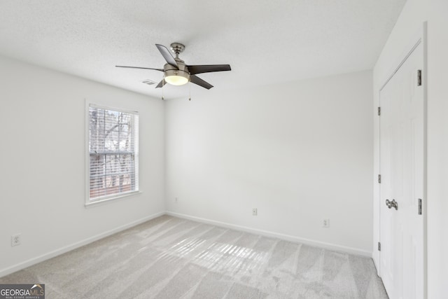 unfurnished bedroom with ceiling fan, light colored carpet, and a textured ceiling