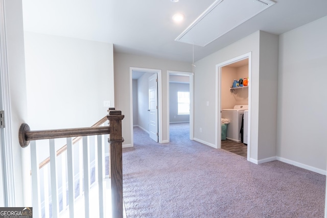 corridor featuring attic access, washing machine and dryer, carpet flooring, and baseboards