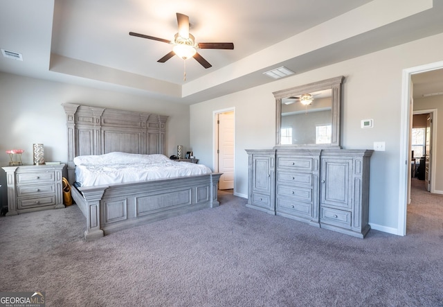 carpeted bedroom with visible vents, a tray ceiling, ceiling fan, and baseboards