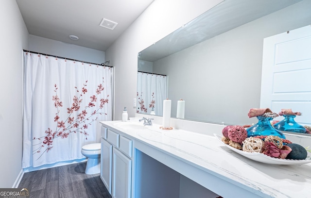 bathroom featuring toilet, wood finished floors, vanity, visible vents, and a shower with curtain