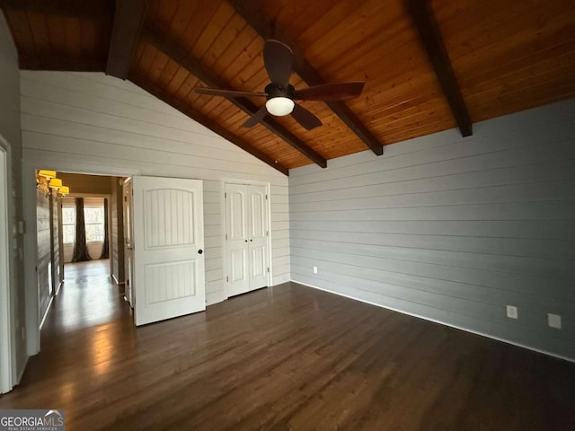 unfurnished bedroom with vaulted ceiling with beams, dark wood-type flooring, wooden ceiling, and wood walls