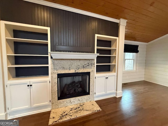 unfurnished living room featuring dark wood-type flooring, a premium fireplace, built in features, and wooden ceiling