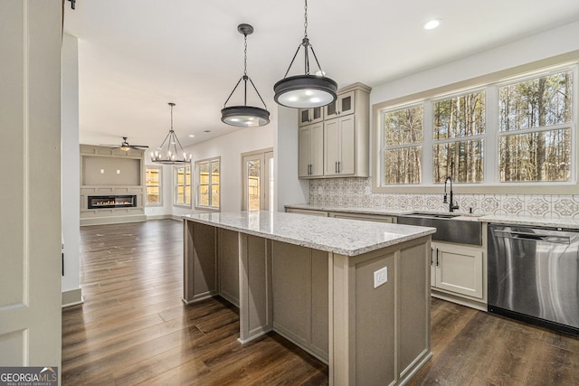 kitchen featuring a kitchen island, tasteful backsplash, dishwasher, sink, and light stone countertops