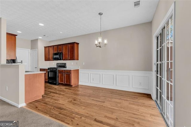 kitchen with pendant lighting, an inviting chandelier, black appliances, light hardwood / wood-style floors, and a textured ceiling