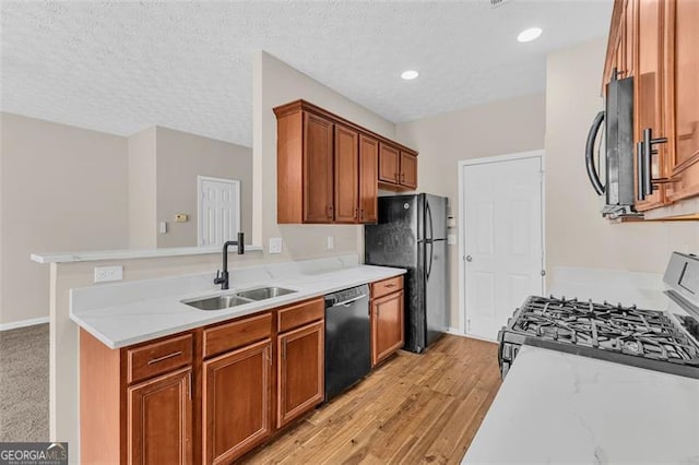 kitchen featuring light stone counters, sink, black appliances, and a textured ceiling