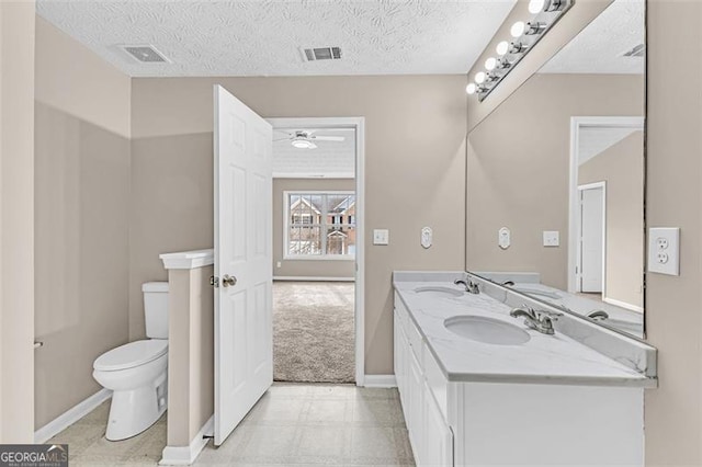 bathroom featuring ceiling fan, vanity, toilet, and a textured ceiling