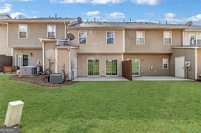 back of house with central AC unit, a patio area, and a lawn