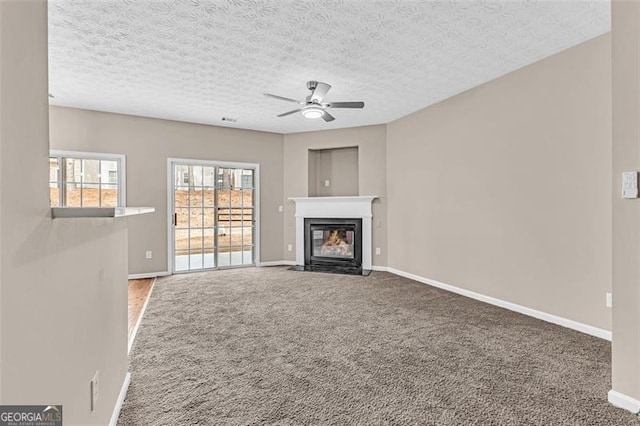 unfurnished living room featuring carpet flooring, a textured ceiling, and ceiling fan