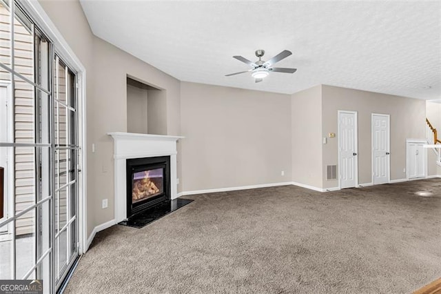 unfurnished living room with ceiling fan, carpet, and a textured ceiling