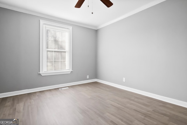 empty room featuring hardwood / wood-style flooring, ornamental molding, and ceiling fan