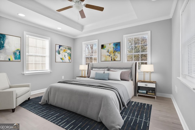 bedroom with a raised ceiling, wood-type flooring, ceiling fan, and multiple windows